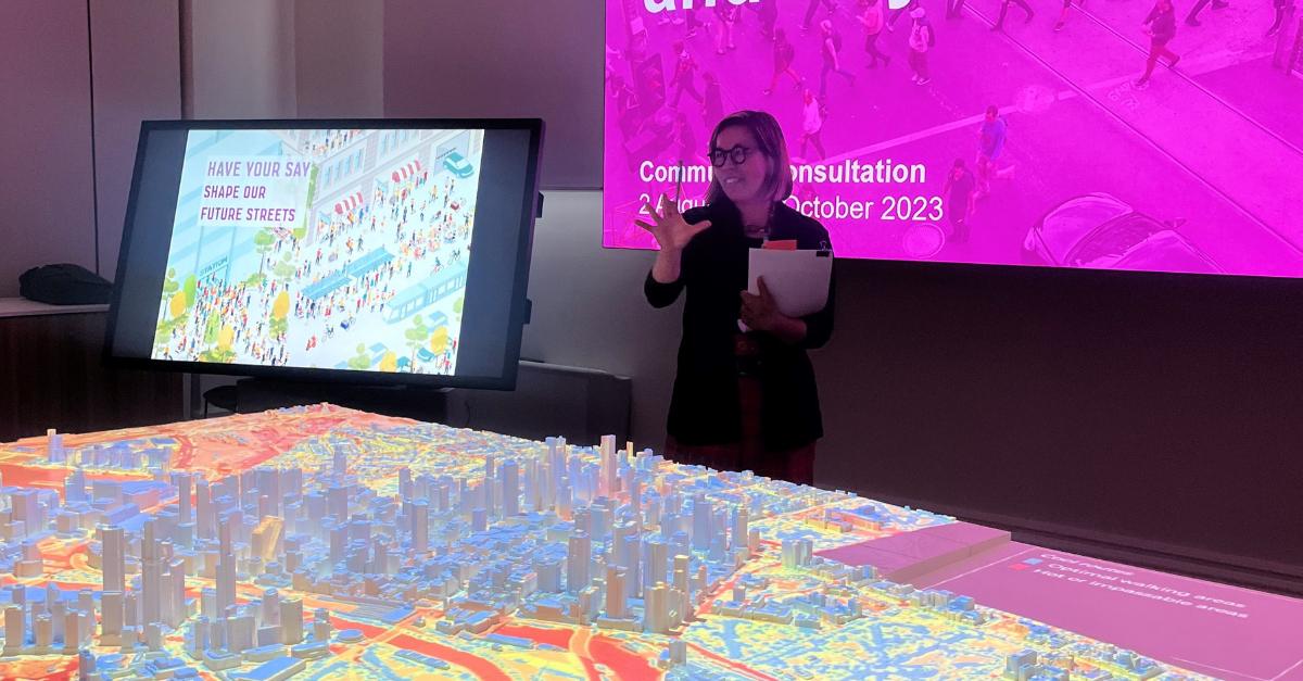 Jocelyn Chiew speaking in front of a 3D model of Melbourne's CBD