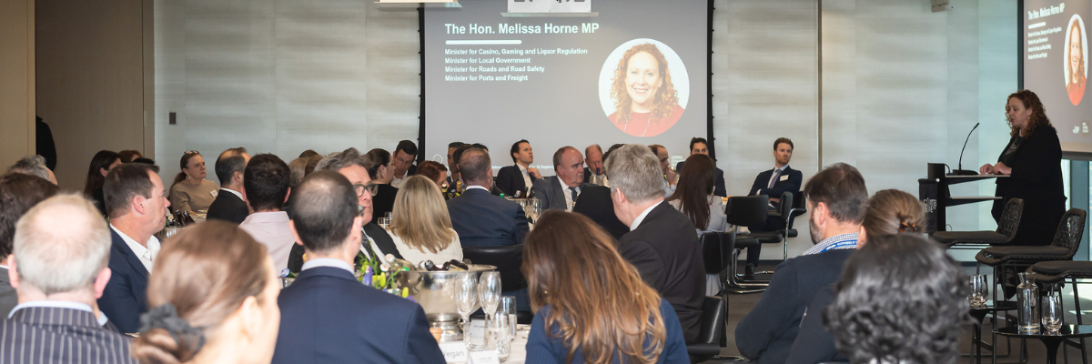 Room of people sat down for lunch while listening to The Hon. Melissa Horne MP speaking at a lectern